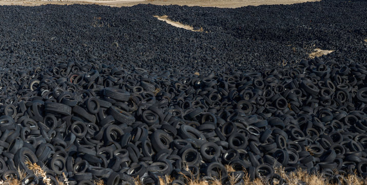 Huge pile of old auto tires between meadow