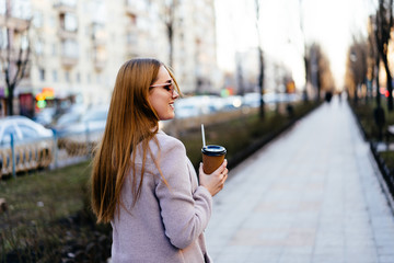 Beautiful young caucasian woman walking along the street in the city. Stylish female model wearing...
