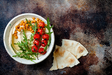 Homemade hummus with roasted cherry tomatoes. Middle Eastern traditional and authentic arab cuisine. Top view, copy space