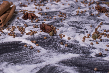 Ingredients for baking dough including flour, sugar, cinnamon, anise star, whisk and rolling pin on dark background. empty space for text, top view, toning