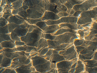 Light stained sea bottom shot through the water surface