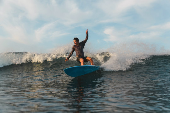 Male surfing between waving water of sea with splashes in Bali, Indonesia
