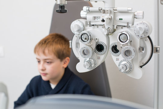 Optician testing a boy's eyes with optometry devices