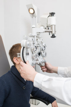 Optician testing a boy's eyes with optometry devices
