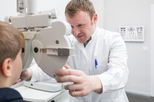 Optician testing a boy's eyes with optometry devices