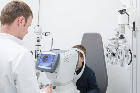 Optician testing a boy's eyes with optometry devices
