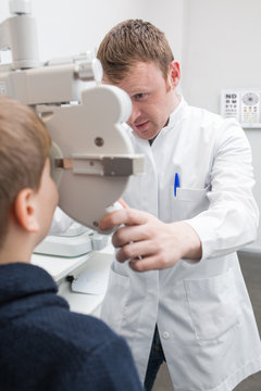 Optician testing a boy's eyes with optometry devices