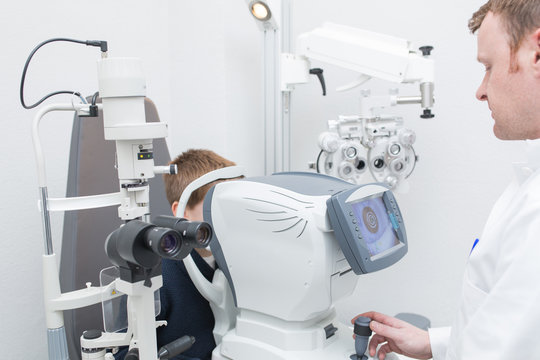Optician testing a boy's eyes with optometry devices