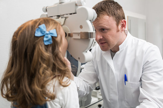 Optician testing a girl's eyes with optometry devices