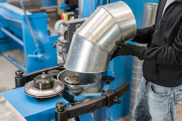 Worker controls the machine. Production rolling tool, electric machine. the production of ventilation and gutters. Tool and bending equipment for sheet metal.