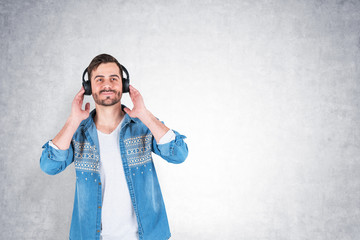 Casual man listening to music, concrete