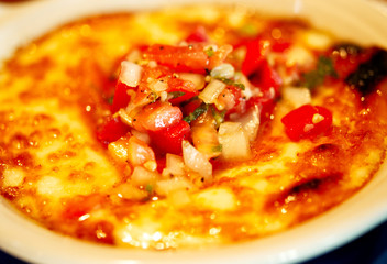 A closeup of a  mozzarella cheese dip with tomatoes, onions and fresh basil. 