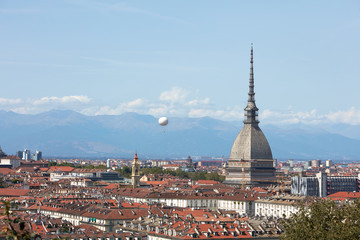 Fototapeta na wymiar Turin city rooftops, Mole Antonelliana tower and hot air balloon in a sunny summer day in Italy