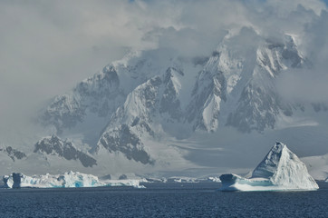 Icebergs Floating off Antartica Continent with Misty Mountains