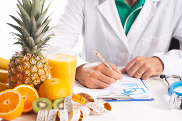 Nutrionist writing a diet plan on table with healthy fruits