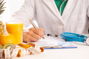 Nutrionist writing a diet plan on table with healthy fruits