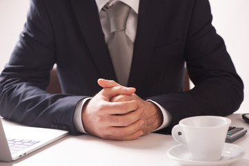 Fototapeta na wymiar Businessman Sitting At Desk With Folded Hands