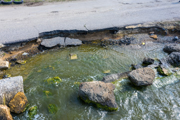 After an earthquake and strong storm in winter and severe destructive frost, asphalt road on landslide swept into sea. Closed road Destroyed asphalt road along sea. Broken asphalt crack and landslides