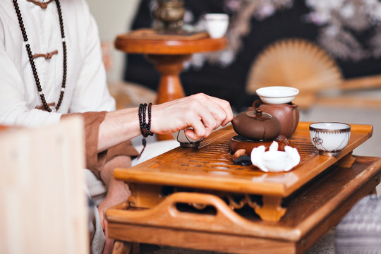 Chinese tea ceremony is performed by tea master in kimono. Man pouring tea from a teapot close-up.