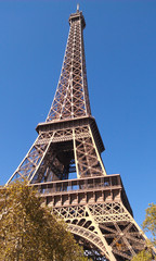looking up to  the eiffel tower in front of the blue sky