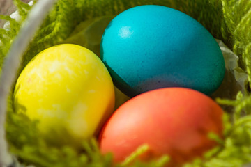 Colored eggs lying in a basket.