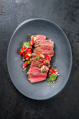 Traditional South American barbecue wagyu roast beef sliced with pico de gallo and salsa verde garnished as top view in a modern design plate