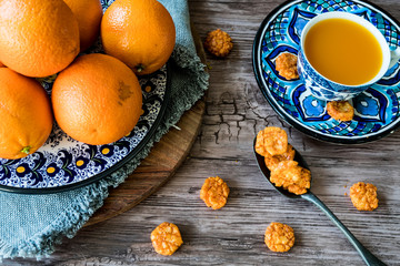 flat lay blue Spanish handmade plate with oranges,  juice and spoon on wooden table