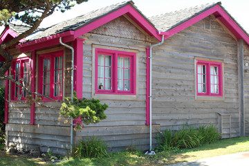 Fototapeta na wymiar Rustic Cottage with Bright Pink Window Frames and Trim on the House