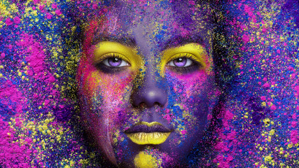 Young pretty girl with colorful creative make-up on holi powder background