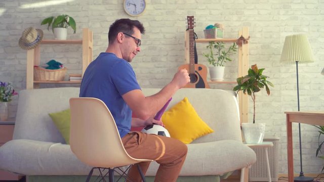 Man shakes a soccer ball with a pump sitting on a chair