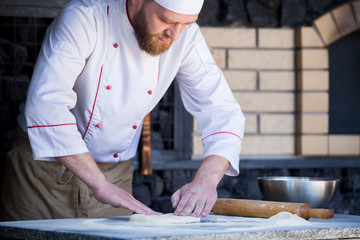cook preparing pizza in a restaurant.