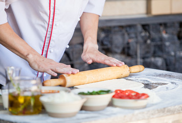 cook preparing pizza in a restaurant.