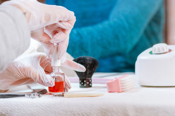 A beautician with hand gloves getting ready to apply red nail polish