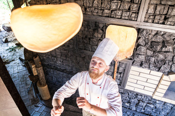 cook preparing pizza in a restaurant.