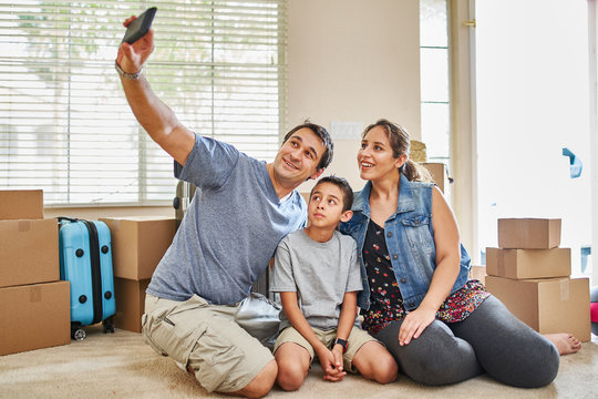 Happy Hispanic Family Taking Selfie After Moving Into New House