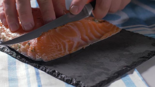 Cutting a homemade marinated salmon with a knife. Slow motion