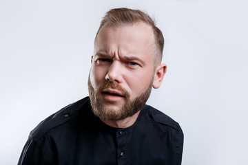 Fototapeta premium Unhappy blonde bearded man with discontent expression, frowns face, recieves bad news from interlocutor