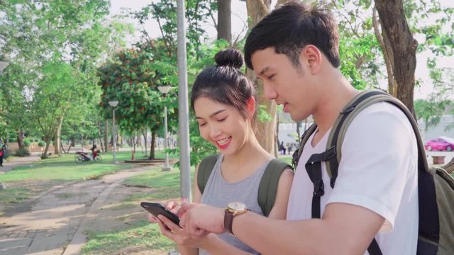 Traveler Asian couple direction on location map in Bangkok, Thailand, couple using mobile phone looking on map find landmark while spending holiday trip. Lifestyle couple travel in city concept.