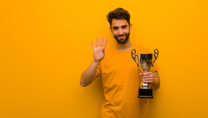 Young man holding a trophy showing number four
