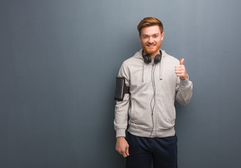 Young fitness redhead man smiling and raising thumb up