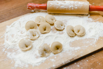 Make dumplings from dough and flour. Chopping board with rolling pin