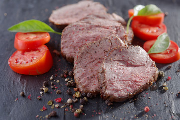 Sliced roast beef and vegetables on a cutting board