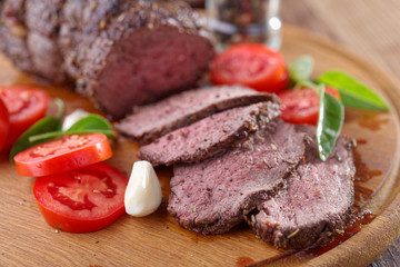Sliced roast beef and vegetables on a cutting board