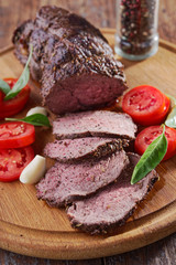 Sliced roast beef and vegetables on a cutting board