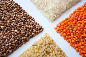 Raw buckwheat, red lentils, bulgur and basmati rice isolated on white background