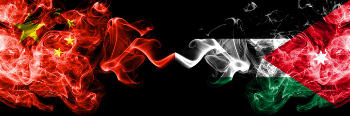 Fototapeta premium Chiny vs Jordania, jordańskie flagi dymne umieszczone obok siebie. Gęste, kolorowe, jedwabiste flagi dymne Chin i Jordanii, Jordanii
