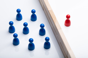 Red And Blue Figurine Pawn Separated By Wooden Blocks