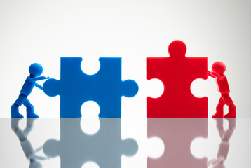 Two Miniature Human Figures Solving Jigsaw Puzzles