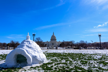 Wide angle view of Capitol Building after Snow against blue skyStorm with the igloo in foreground,...