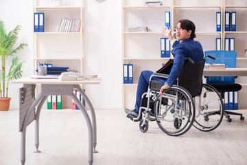 Young male employee in wheelchair working in the office 